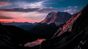 A Mountain Range With A Lake And Sunset Wallpaper