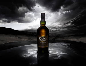 A Mysterious Sip - Ardbeg Uigeadail Whisky Under A Stormy Sky Wallpaper