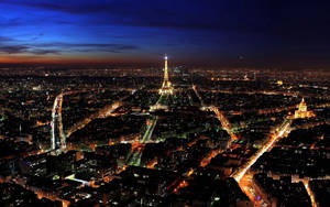 “a Nighttime View Of The City Of Lights” Wallpaper