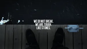 A Person Standing On A Dock With The Words We Don't Break We Are Tough Life's Stones Wallpaper