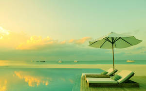 A Pool With Lounge Chairs And An Umbrella Wallpaper