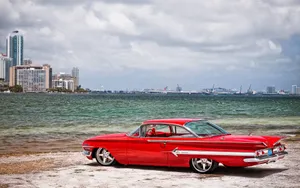 A Red Car Parked On The Beach Wallpaper