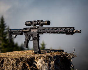 A Rifle Sits On Top Of A Stump With A Scope Wallpaper