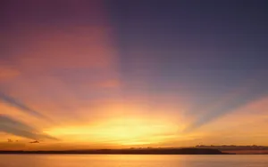 A Serene Sunrise Above The Horizon Wallpaper