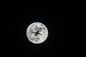A Silhouetted Airplane Soaring Against A Nocturnal Starry Sky Wallpaper