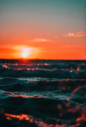 A Sunset Over The Ocean With Waves Wallpaper