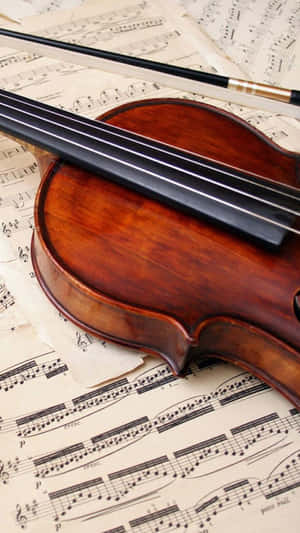 A Violin Resting On Music Sheets Wallpaper