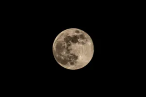 A Waning Full Moon Against The Backdrop Of A Starry Night Sky. Wallpaper