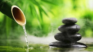 A Waterfall Is Pouring Water Over A Bamboo And Stone Wallpaper