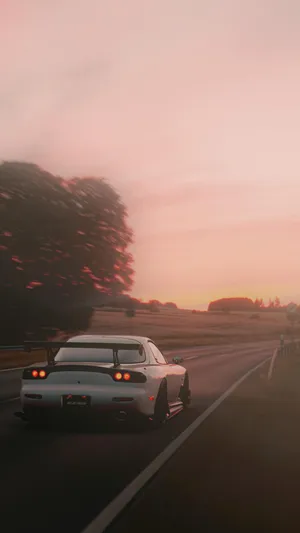 A White Car Driving Down A Road Wallpaper