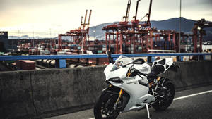 A White Ducati Motorcycle In A Container Port Wallpaper