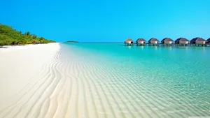 A White Sandy Beach With Huts And A Blue Ocean Wallpaper