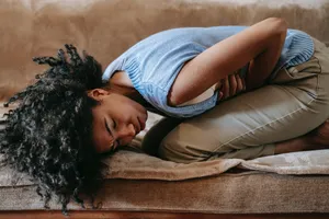 A Woman Is Lying On A Couch With Her Stomach Hurting Wallpaper