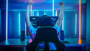 A Woman Is Sitting In Front Of A Computer With Her Arms Raised Wallpaper