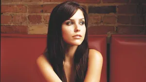 A Woman Sitting On A Red Couch With Long Hair Wallpaper