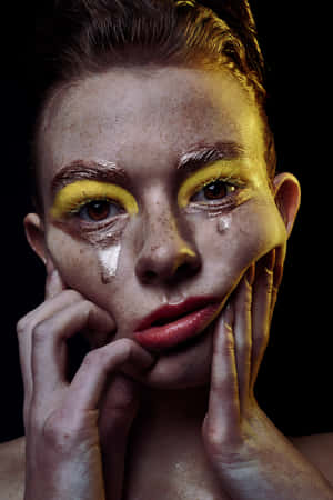 A Woman With Yellow Makeup And A Face Covered In Tears Wallpaper