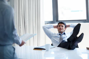 Arrogant Boss Nonchalantly Resting Feet On Office Desk Wallpaper