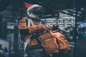 Astronaut In Space Wearing Orange Suit Wallpaper
