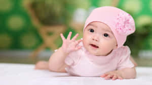 Baby Girl Wavingin Pink Outfit Wallpaper