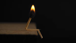 Bended Lit Matchstick Against Dark Screen Wallpaper