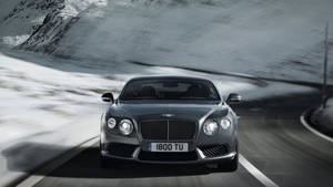Bentley Speeding In Snowy Mountains Wallpaper