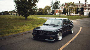 Black Bmw M3 In Residential Road Wallpaper