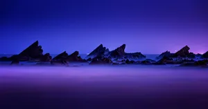 Blue And Purple Sunset With Rock Silhouettes Wallpaper