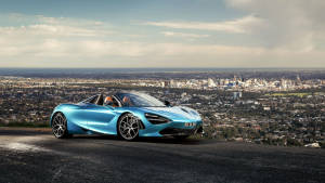 Blue Mclaren Spyder Near City Wallpaper