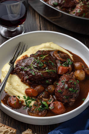 Bowl Of Creamy Coq Au Vin Near A Glass Of Wine Wallpaper