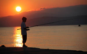 Boy Fishing During Sunset Wallpaper