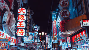 Bright Shop Signs Light Up The Nighttime Street In Tokyo, Japan Wallpaper