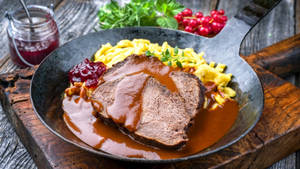 Caption: Authentic German Sauerbraten Dish With Redcurrant Jam And Basil Wallpaper