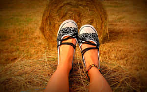 Caption: Elegant Girl Feet Sporting Black And White Shoes On Hay Bale Wallpaper