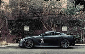 Caption: Powerful Nissan Skyline Gtr R35 Parked Behind Mesh Fencing. Wallpaper