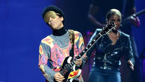 Caption: Prince Performing On Stage Wallpaper