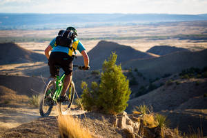 Caption: Thrilling Mountain Biking Downhill Adventure Wallpaper