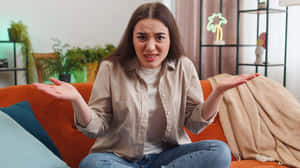 Confused Woman On Couch Wallpaper