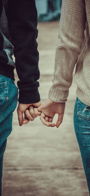 Cute Holding Hands Couple In Sweatshirts Wallpaper