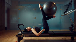 Dedicated Fitness Enthusiast Practicing Pilates With A Stability Ball Wallpaper