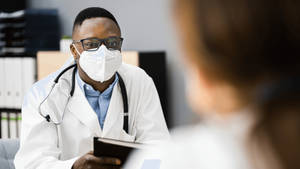 Dedicated Physician Wearing A Protective Mask Wallpaper