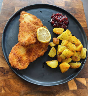 Delectable Wiener Schnitzel Served On A Black Platter Wallpaper