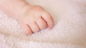 Delicate Baby Hand Resting On Soft Towel Wallpaper