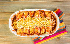 Delicious Enchilada Platter Topped With Cheddar Cheese. Wallpaper