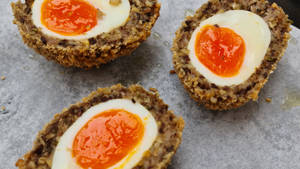 Delicious Traditional British Scotch Eggs Dish On Paper Wallpaper