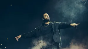 Drake Is Standing On Stage With His Arms Outstretched Wallpaper