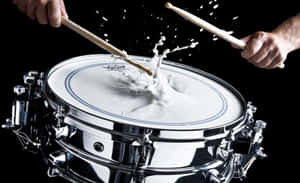 Dynamic Drumstick Impacton Snarewith Splash Wallpaper