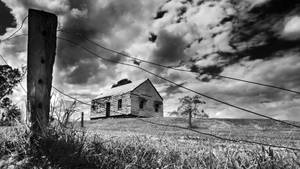 Eerie Haunted House Under A Cloudy Sky Wallpaper