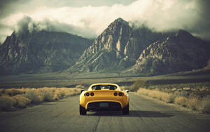 Effortless Power - Yellow Lotus Car Cruising Through The Arid Desert Wallpaper