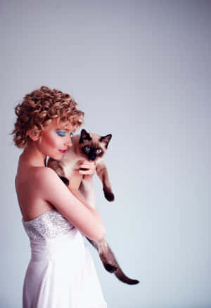 Elegant Woman Holding Siamese Cat Wallpaper