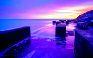Enjoy The Beauty Of Nature As The Sun Dips Over The Horizon Casting A Beautiful Blue And Purple Sunset. Wallpaper